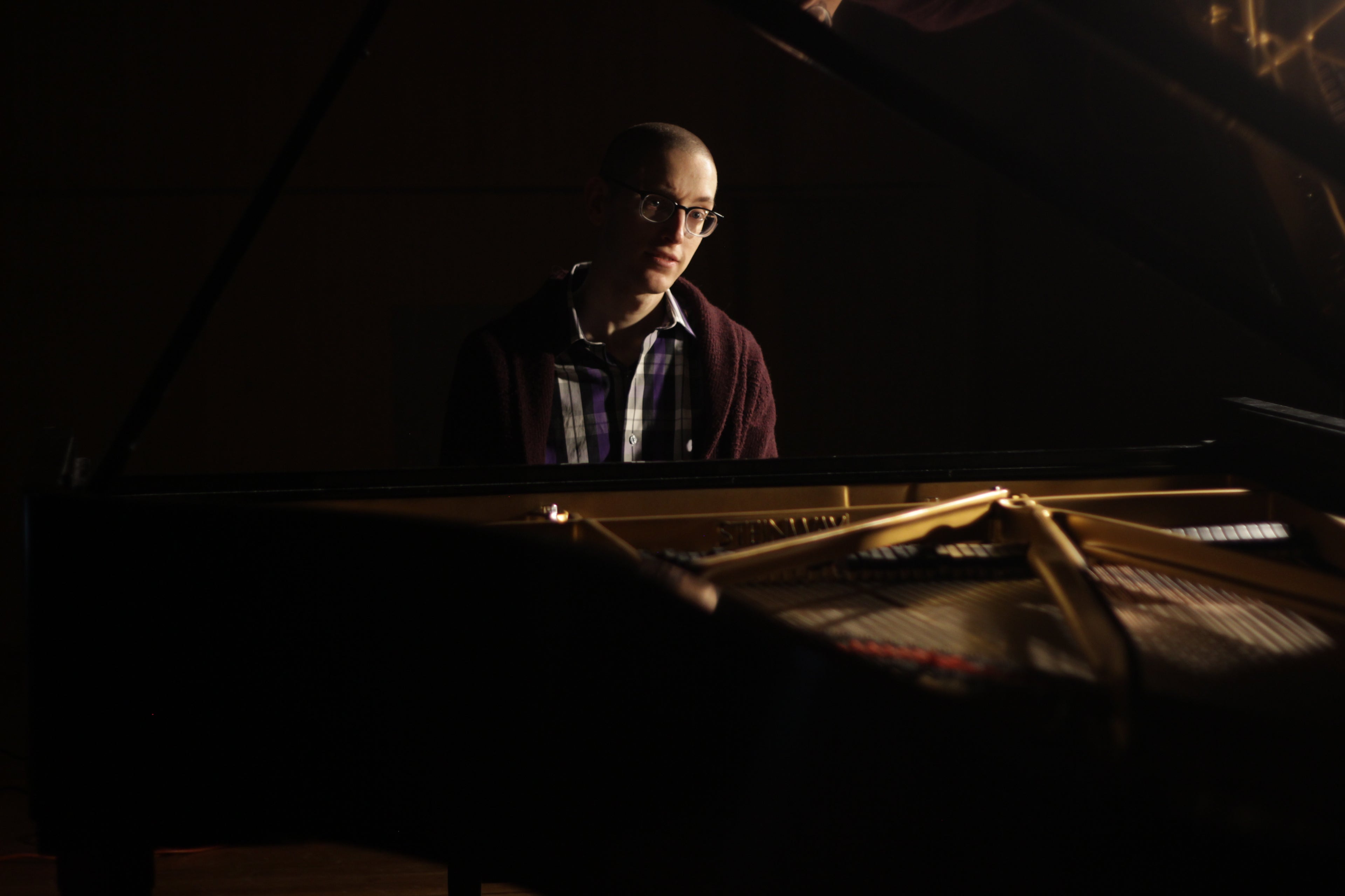 Person playing a piano in a dimly lit room
